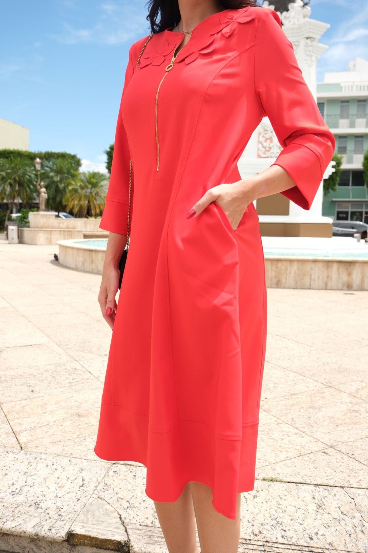 Model wearing orange A-line dress with floral appliqué and gold front zipper – side view