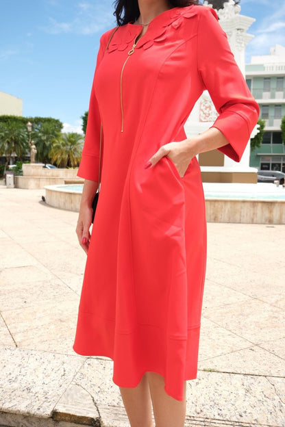 Model wearing orange A-line dress with floral appliqué and gold front zipper – side view
