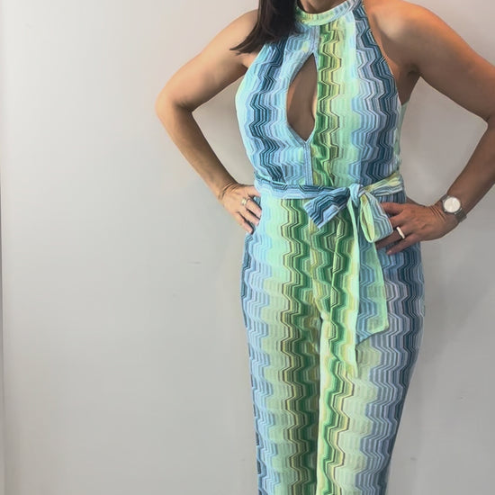Model wearing green wave halter jumpsuit with flattering halter neckline and flowing wide-leg silhouette.