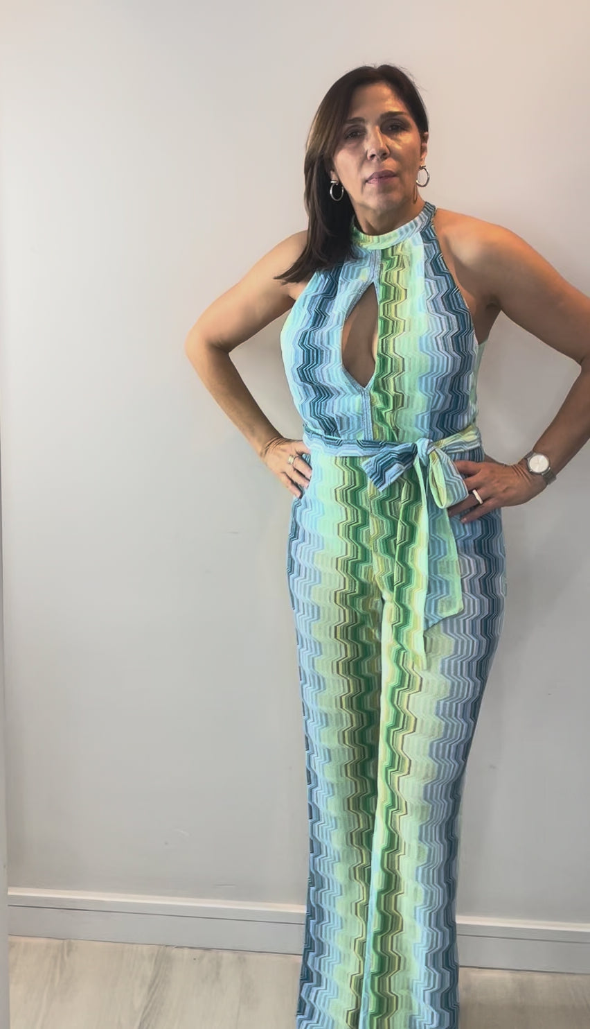 Model wearing green wave halter jumpsuit with flattering halter neckline and flowing wide-leg silhouette.
