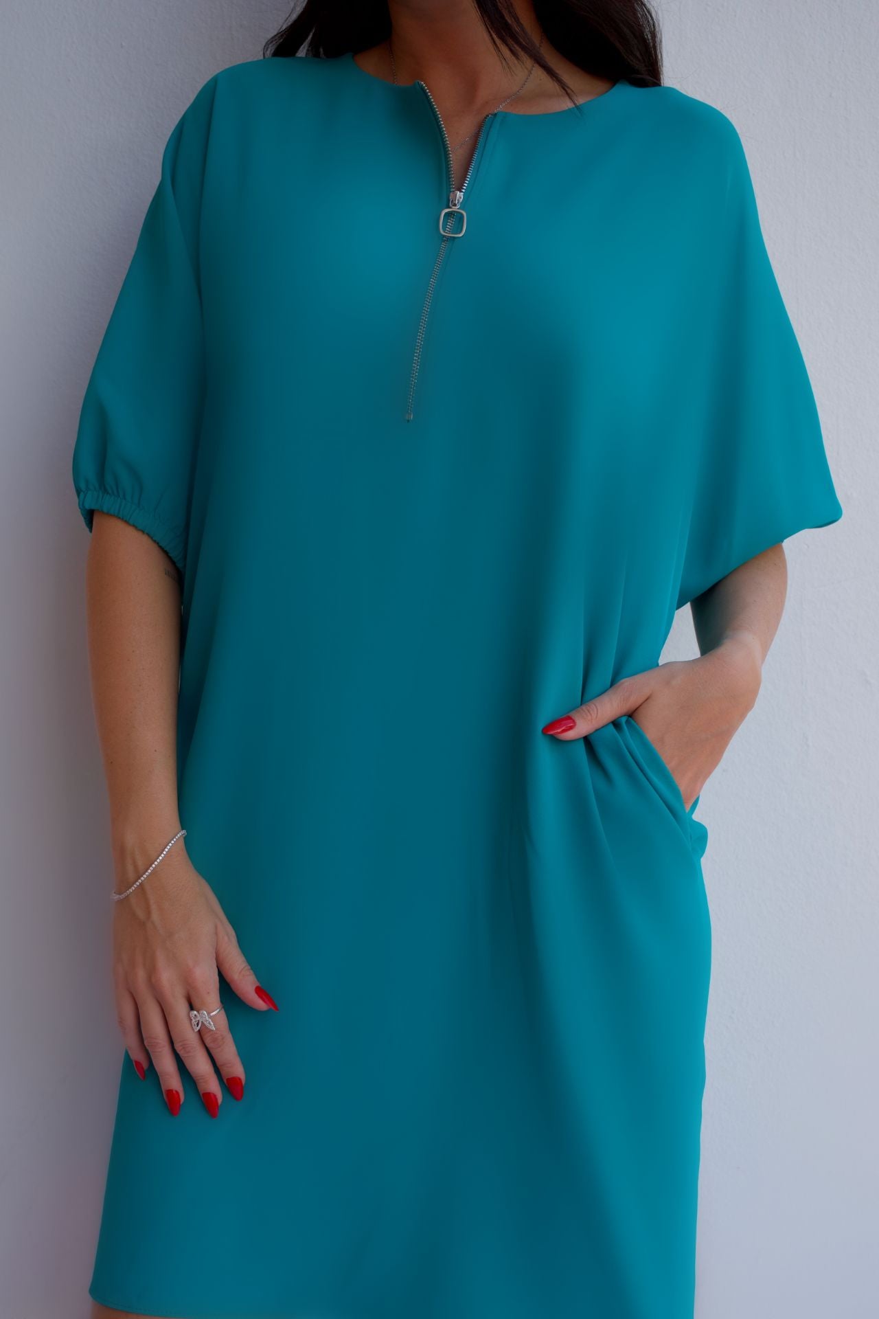 Closeup of turquoise relaxed fit zip dress with pockets, styled for an effortless day-to-night look.