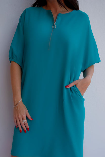 Closeup of turquoise relaxed fit zip dress with pockets, styled for an effortless day-to-night look.
