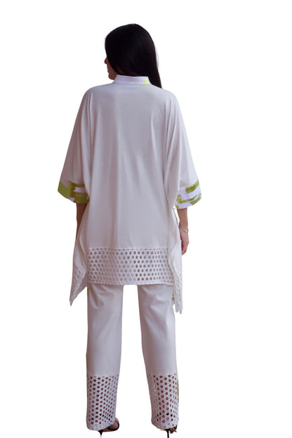 Woman wearing an elegant white eyelet detail pant set with relaxed high-low top and straight-leg pants.