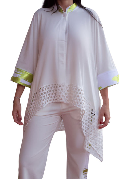 Woman wearing an elegant white eyelet detail pant set with relaxed high-low top and straight-leg pants.