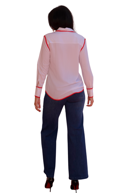 Model wearing a white long sleeve blouse with tangerine trim detail and button-front design.