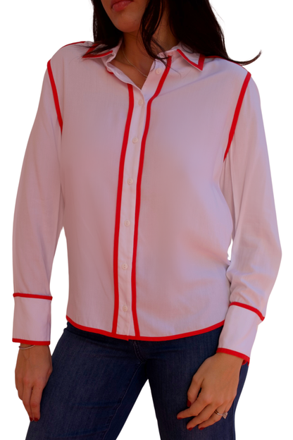 Model wearing a white long sleeve blouse with tangerine trim detail and button-front design.
