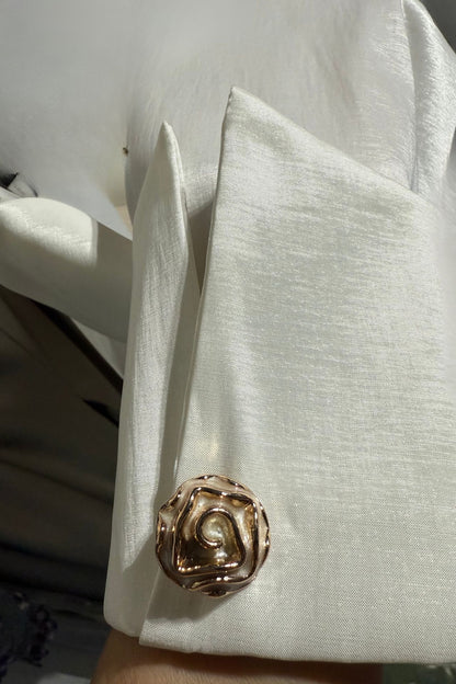 Close-up of a sleeve with a decorative button on a plain background.