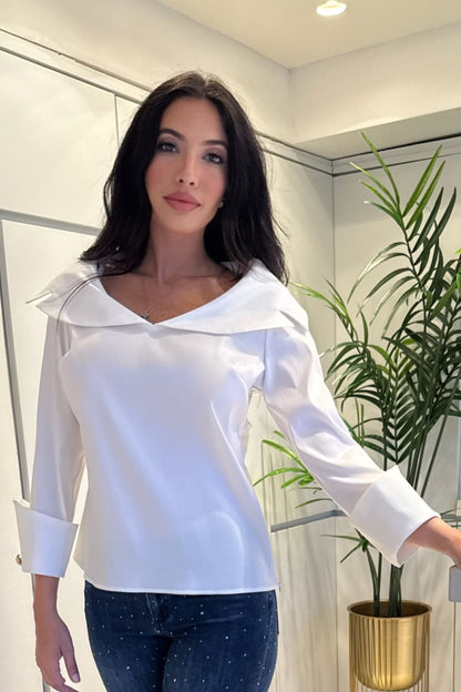 Woman wearing a white sailor collar blouse with wide statement cuffs paired with embellished denim.